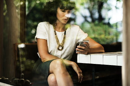 woman sitting on chair while holding smartphone thumbnail