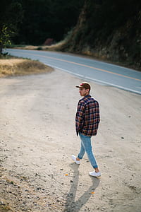 man in blue jeans walking beside road thumbnail