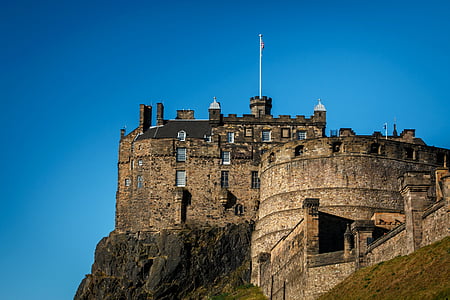 brown castle on cliff under blue sky during daytime thumbnail