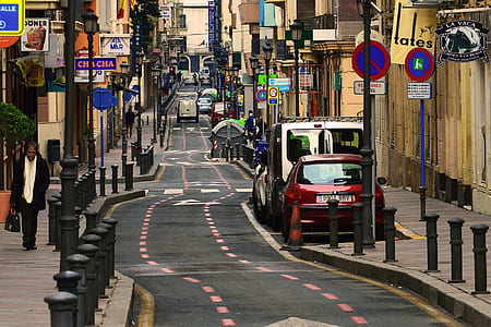 woman walking on pathway near red car parked in front of beige building thumbnail