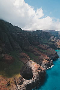 gray and green stone hills near bodies of water under cloudy sky at daytime thumbnail