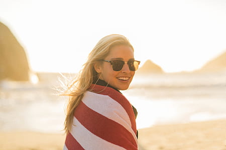 woman wrapped with red and white striped towel wearing sunglasses on seashore thumbnail