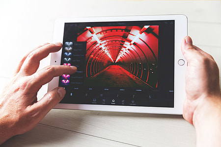 A man edits a photo in Lightroom photo app for iPad tablet computer thumbnail