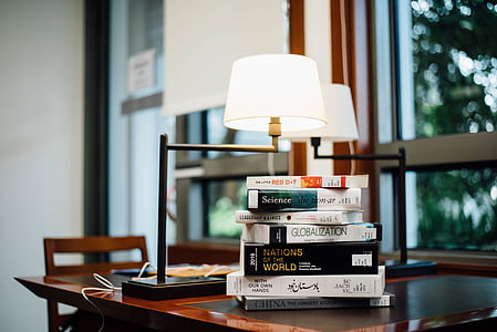 lighted white table lamp beside assorted books thumbnail
