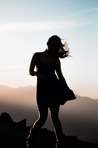 silhouette of woman standing on boulder thumbnail