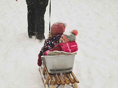 two toddler riding on snow sled thumbnail