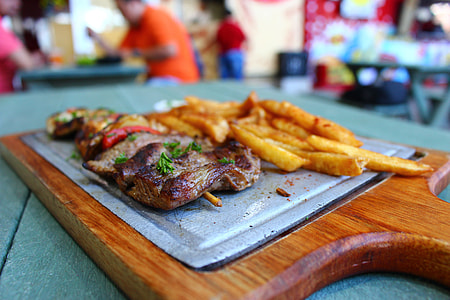 selective focus photography of fried potatoes and grilled meat on chopping board thumbnail