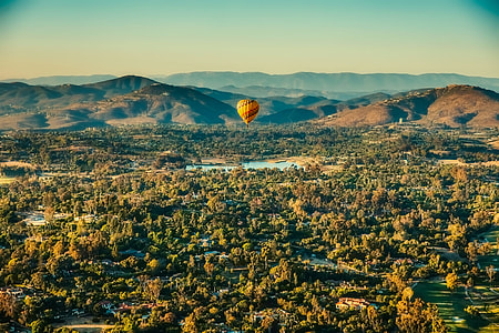 aerial photography of yellow air balloon floating over forest during daytime thumbnail
