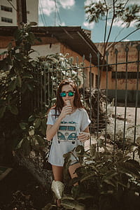 woman in white and teal shirt standing beside fence thumbnail