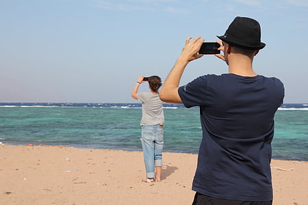 man and woman taking photo of ocean thumbnail