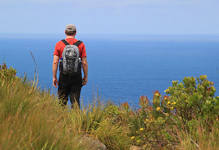 man wearing backpack standing near cliff thumbnail