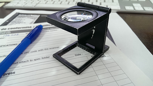 black magnifying glass on white printing paper near blue ballpoint pen thumbnail