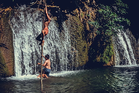 Children Climbing On Tree Branch Near Waterfalls thumbnail