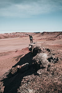 A young caucasian hiker peaks over a rocky edge thumbnail
