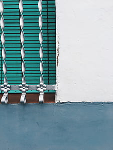 teal window blinds behind gray metal window grilles thumbnail
