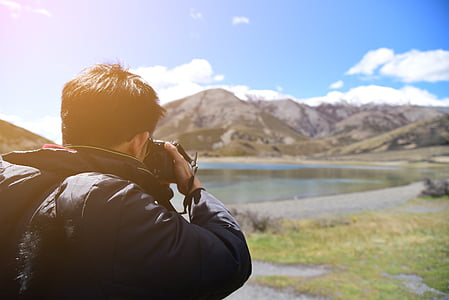 man taking photo of lake during daytime thumbnail