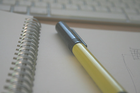 black ballpoint pen on white spiral book shallow focus photography thumbnail