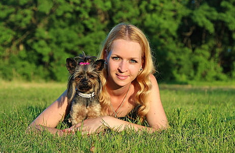 woman wearing black tank top lying on green grass field with black and tan Yorkshire terrier puppy during daytime thumbnail