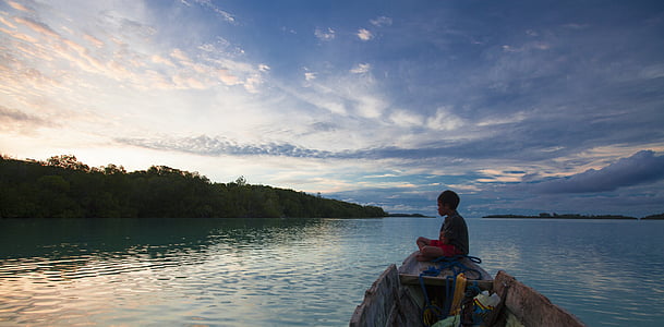 boy riding boat under calm blue sky thumbnail