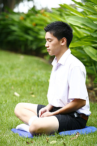 man wearing white shirt meditating on green grass thumbnail