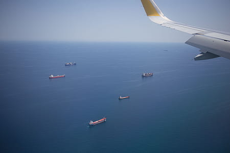 Aerial view of cargo ships in the ocean from the airplane window with aircraft wing in the fame thumbnail
