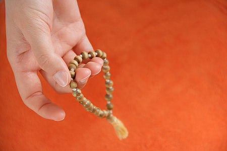 person holding brown prayer beads thumbnail