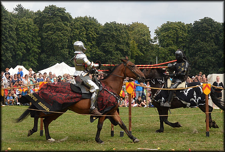 two person riding horses while holding red wooden sticks taken during daytime thumbnail
