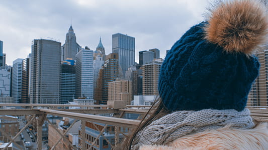 Woman Wearing Bobble Hat Staring at High-rise Buildings thumbnail