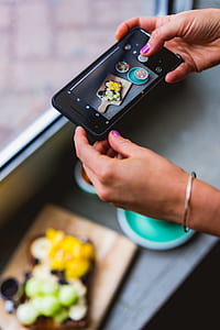 close-up photography of person holding black smartphone while capturing sliced vegetables thumbnail