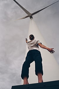 person in white shirt standing below wind turbine thumbnail