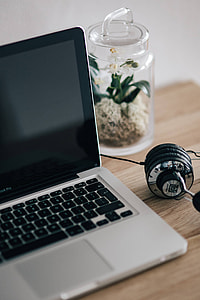 MacBook Pro with headphones on a wooden desk thumbnail