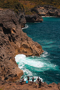 people on mountain cliff near body of water thumbnail
