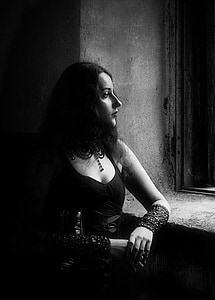 grayscale photo of woman standing beside window thumbnail