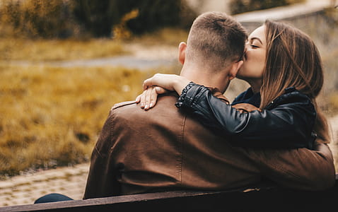 woman kissing the forehead of a man while sitting on bench thumbnail