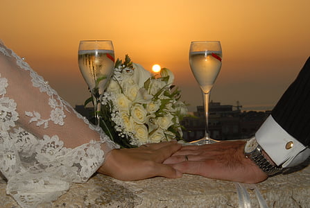 bride and groom hands on white table cloth under sunset thumbnail
