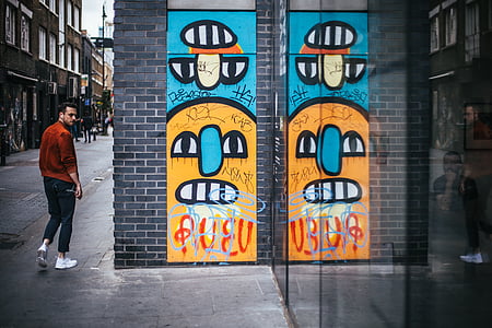man standing beside concrete wall with graffiti thumbnail