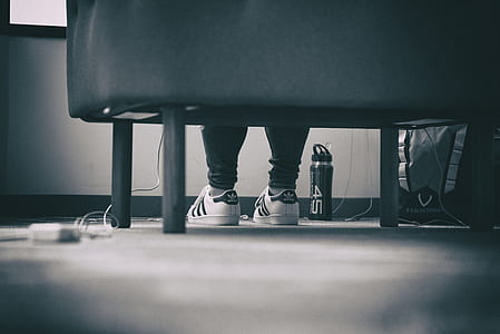 person sitting on sofa on white-and-black adidas Superstar shoes thumbnail