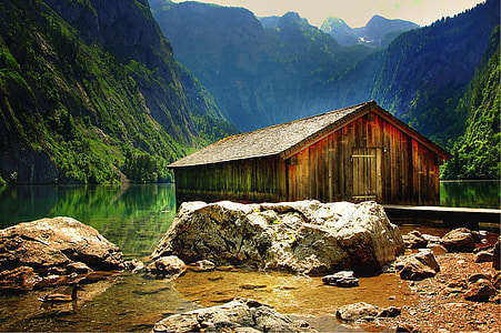 brown wooden rest house on lake surrounded by mountains during daytime thumbnail