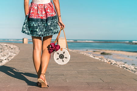 Woman Wearing Mini Skirt Holding Round Wicker Bag thumbnail
