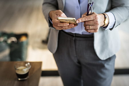 person wearing suit jacket holding smartphone thumbnail
