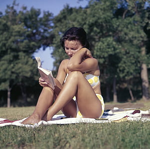 woman sitting on white textile reading a book thumbnail