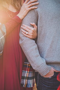woman in red V-neck dress holding man arm thumbnail