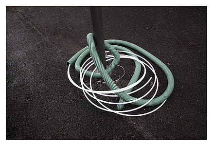 white wire in green plastic hose on brown surface thumbnail