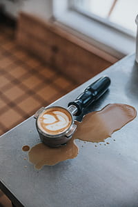 black espresso maker pot with coffee art on top of table thumbnail