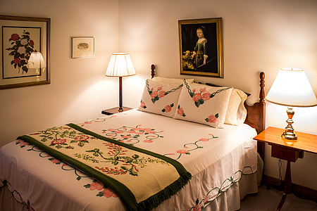 two lighted lamps beside white and red floral bed thumbnail