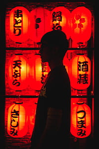 man's silhouette near red paper lamps thumbnail