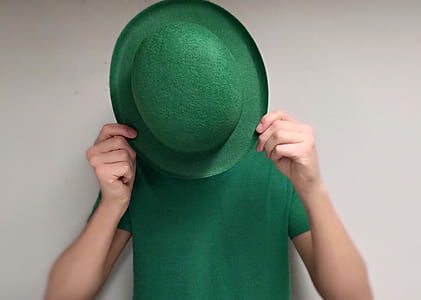 person wearing green shirt covering face with green hat thumbnail