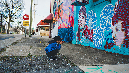 boy sitting near faces graffiti thumbnail