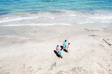 aerial view of group of women standing on white sand near seashore thumbnail
