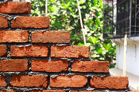 brown brick wall near white house close-up photography thumbnail